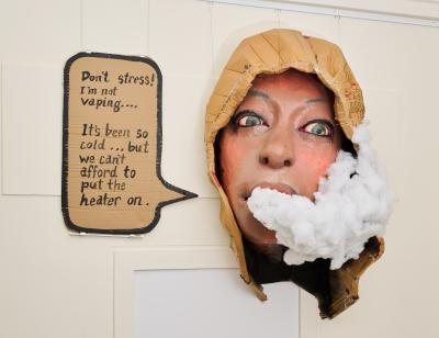 A sculpture of a person's face with a cloud coming out of their mouth, saying, 'Don't stress! I'm not vaping... It's been soon cold... but we can't afford to put the heater on.'